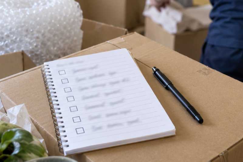 Liste de tâches sur un bloc-notes posé sur un carton