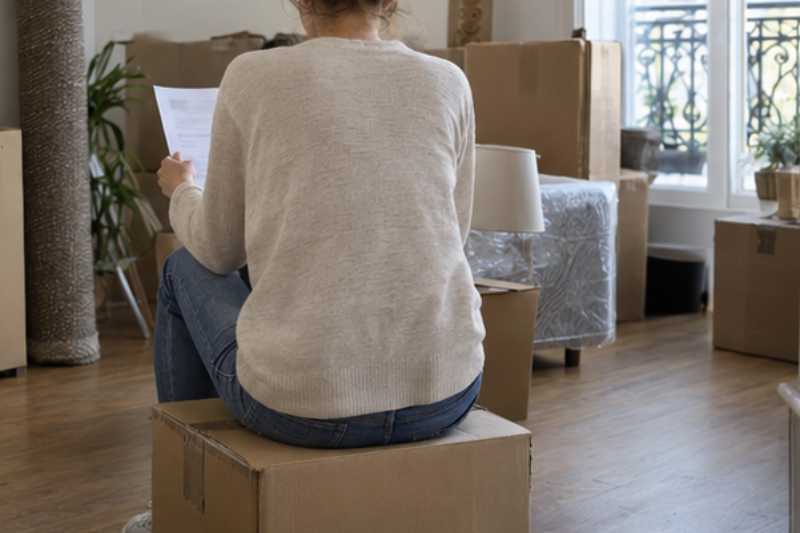Client qui relit un document assis sur un carton, de dos