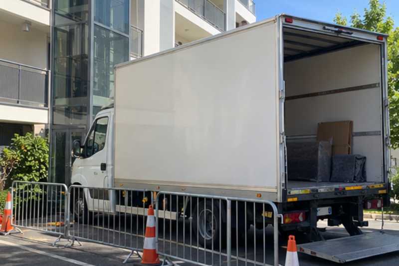 Camion blanc sur une place réservée délimitée par des barrières, Asnières-sur-Seine