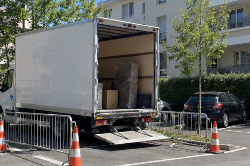 Camion blanc sur une place réservée délimitée par des barrières, Issy-les-Moulineaux
