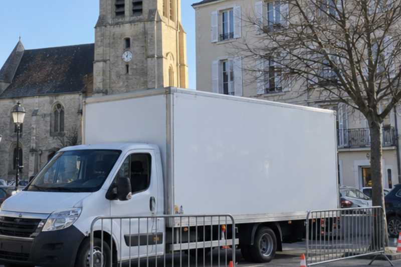 Camion blanc sur une place réservée délimitée par des barrières, L'Isle-Adam