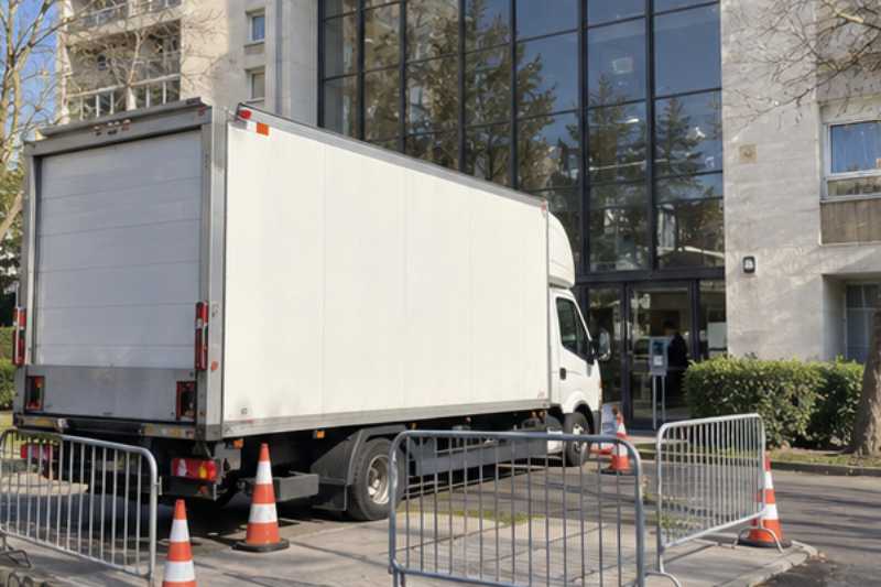 Camion blanc sur une place réservée délimitée par des barrières, Montreuil