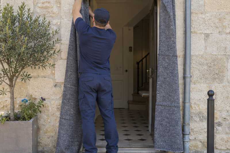 Déménageur qui protège l'encadrement de porte avec des couvertures, Othis