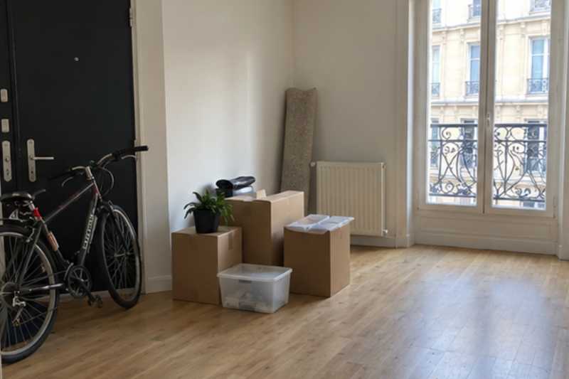 Studio presque vide avec quelques cartons et un vélo près de la porte