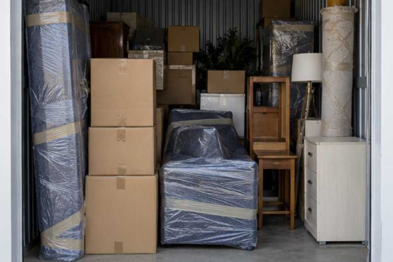 Box de stockage rempli de cartons et de meubles sous housses