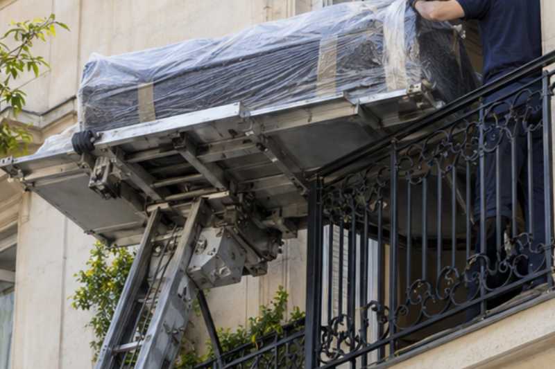 Opérateur qui guide la plateforme d'un monte-meuble au niveau d'un balcon