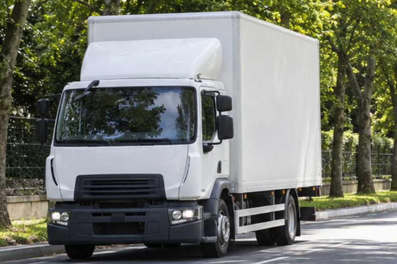 Camion de déménagement blanc roulant sur une route d'Île-de-France bordée d'arbres